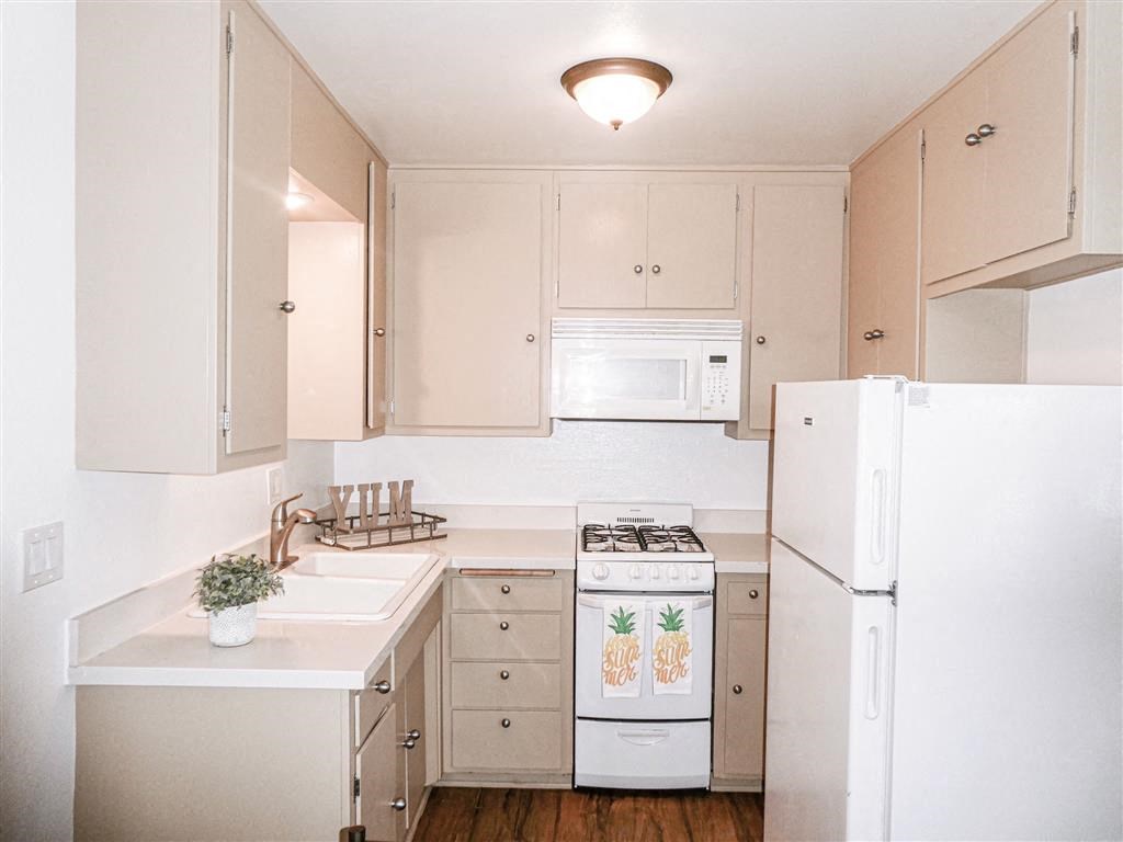 a kitchen with white appliances and tan cabinets