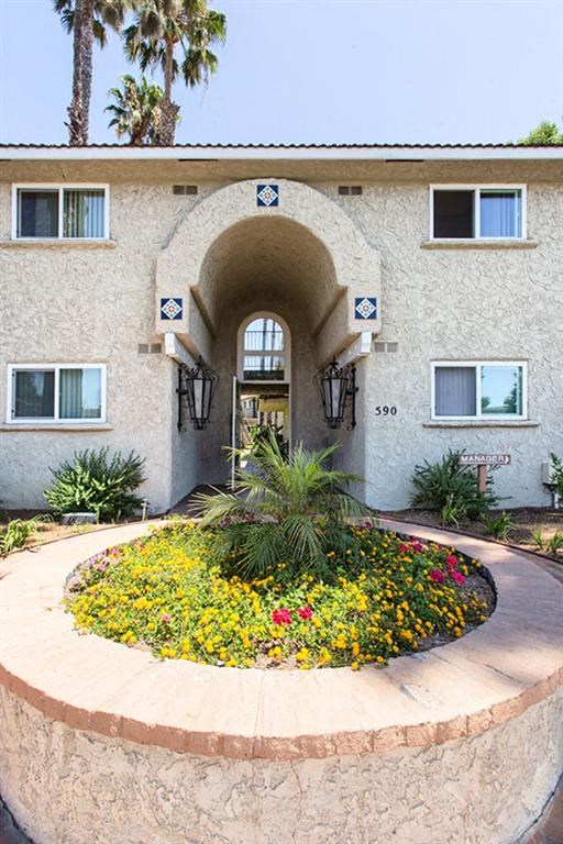 a building with an arch and a flower garden in front of it