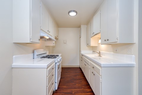 A white kitchen with a stove and sink.