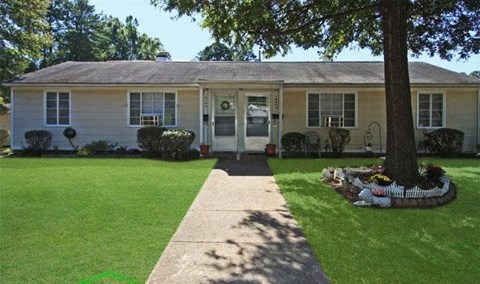 a white house with a lawn and a tree