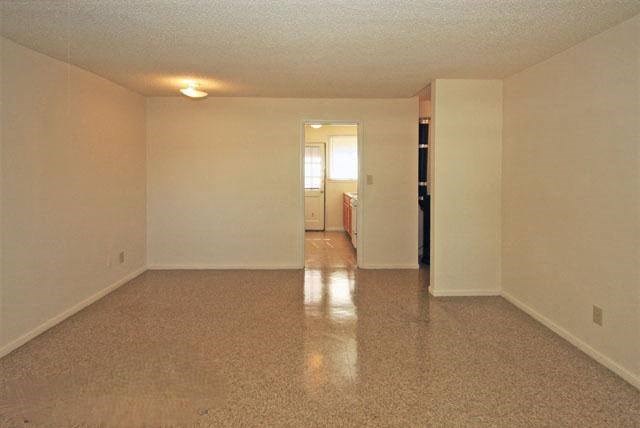an empty living room with white walls and a tile floor