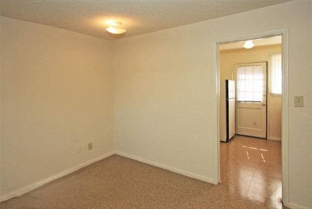 an empty living room with a door to a kitchen