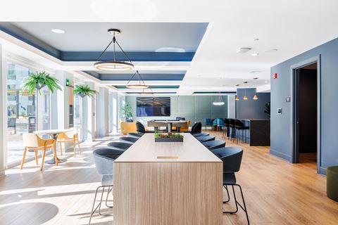 a communal table and chairs in a lobby with blue walls and windows