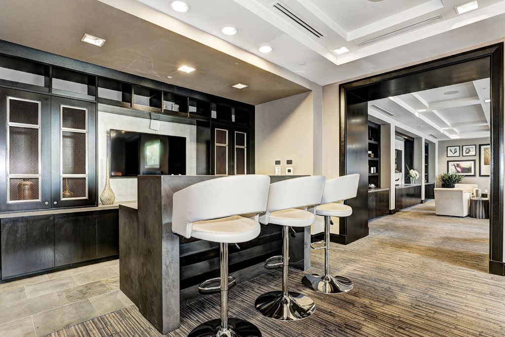 a lobby with white chairs and a bar with stools