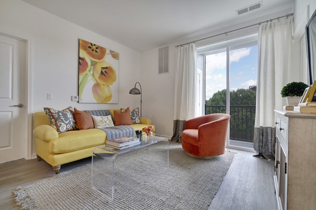 a living room with a yellow couch and a chair and a large window