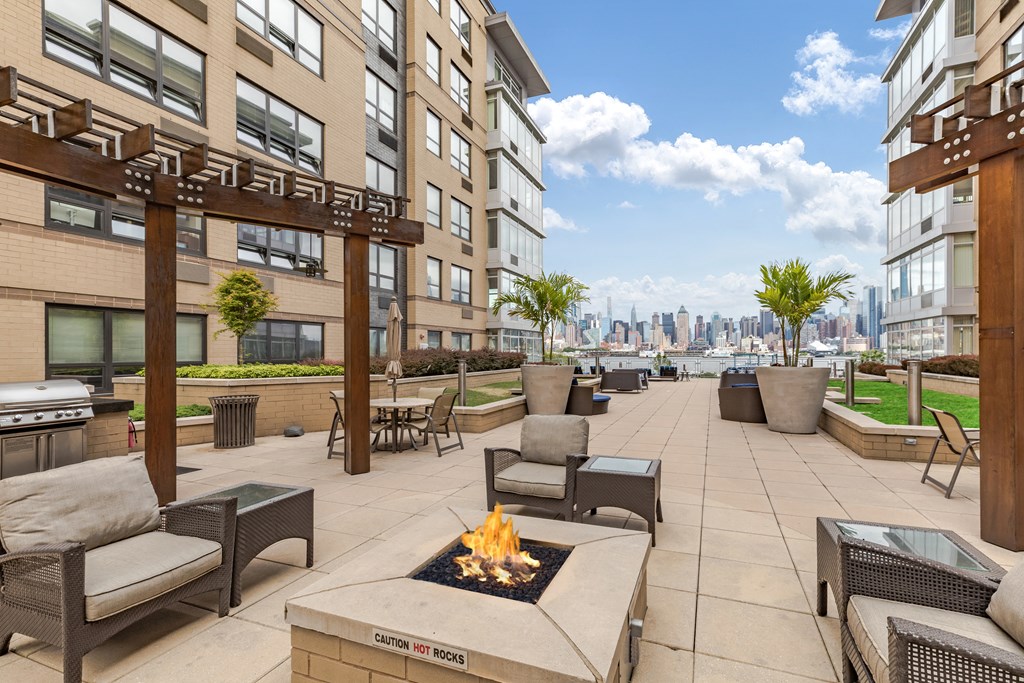 an outdoor patio with a fire pit and chairs and a view of the city