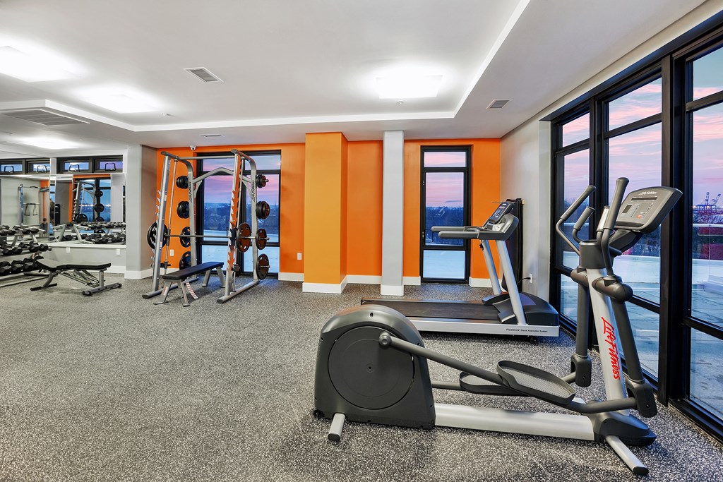 a gym with exercise equipment and windows with a view of the water