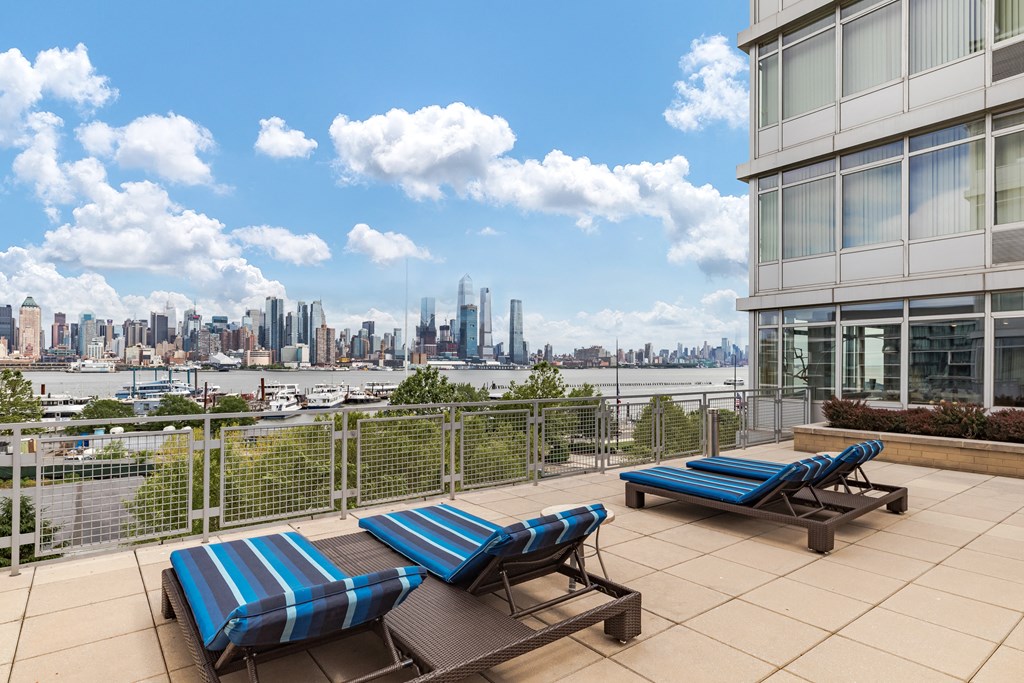 an outdoor patio with lounge chairs and a view of the city