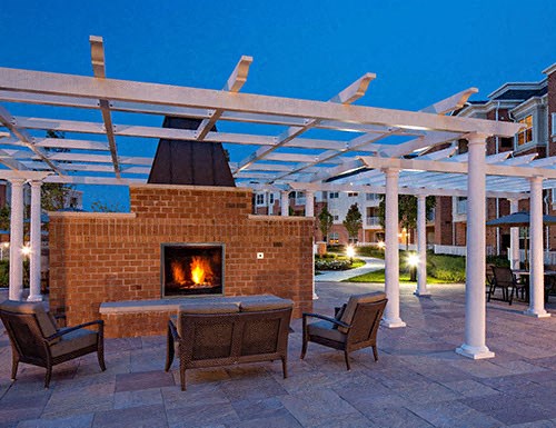 a brick fireplace and patio with chairs and a pergola