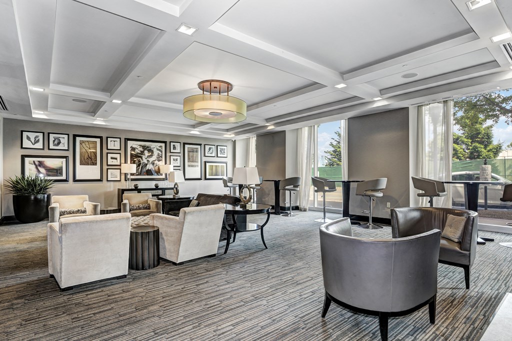 a lounge area with chairs and tables and a large window