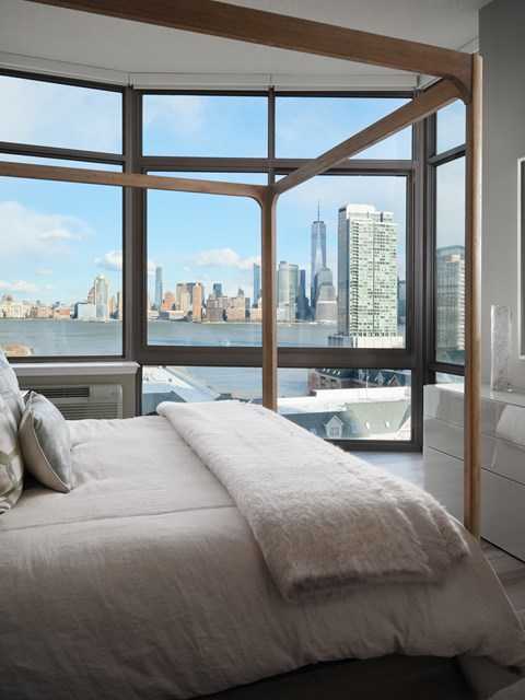 A bedroom with a large bed and a view of the city skyline.