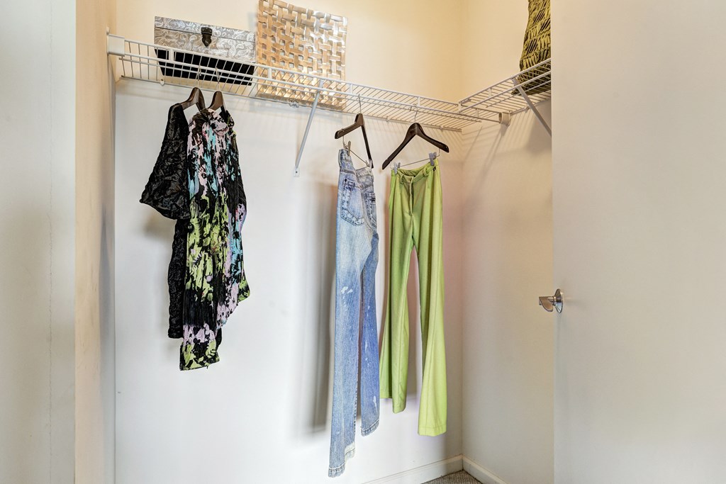 a closet with two dresses and a rack with clothes on it