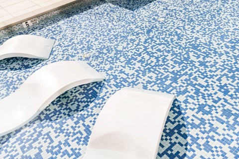 A white object is floating in a blue and white tiled pool.