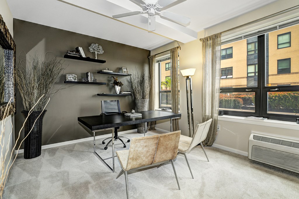 a home office with a large window and a table with chairs
