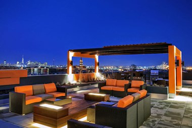 a terrace with couches and a fire pit overlooking a city at night