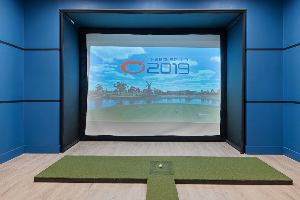 A golf simulator room with a screen showing a golf course and the text "The Golf Club 2019".
