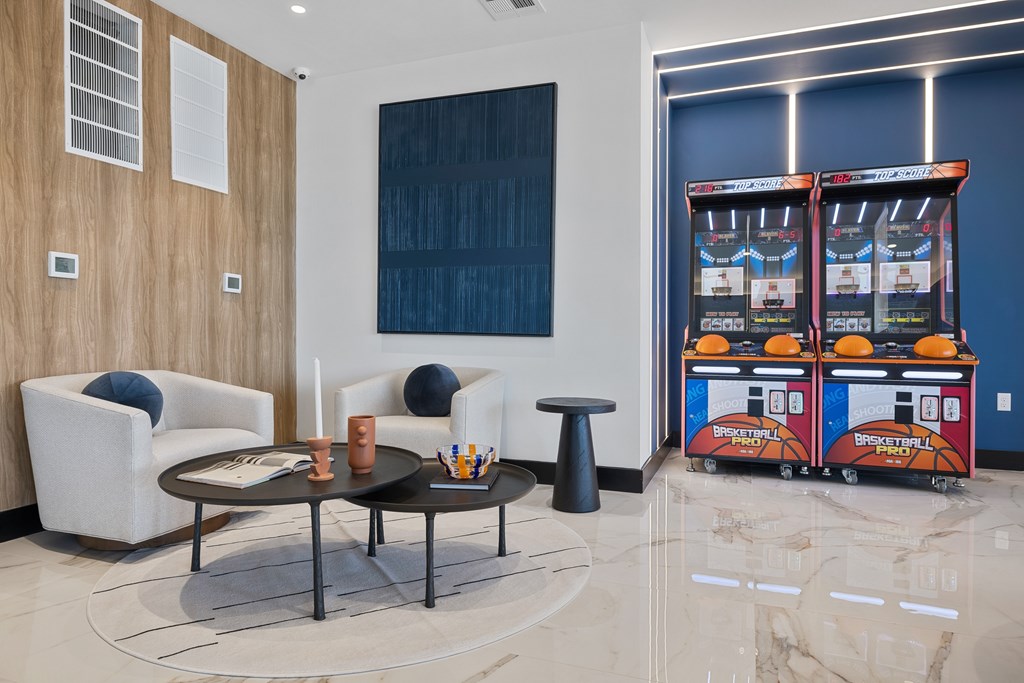 A basketball arcade game machine sits in a room with a white couch and a black coffee table.