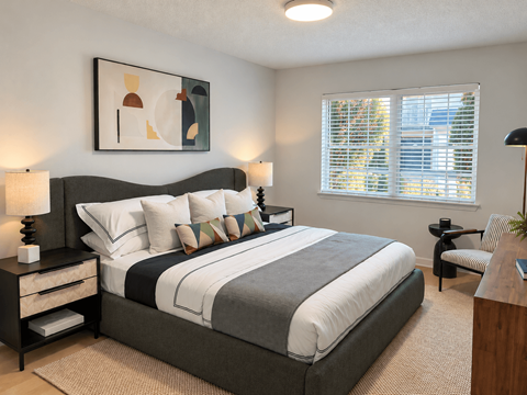 A bedroom with a large bed and a painting on the wall.