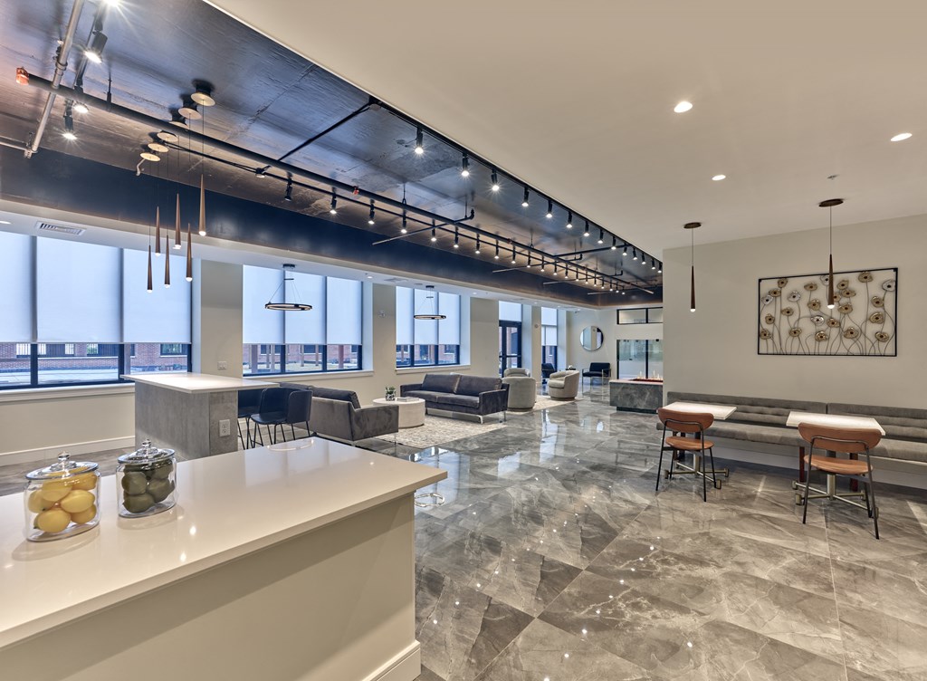 a communal area with a bar and tables and chairs in a room with large windows