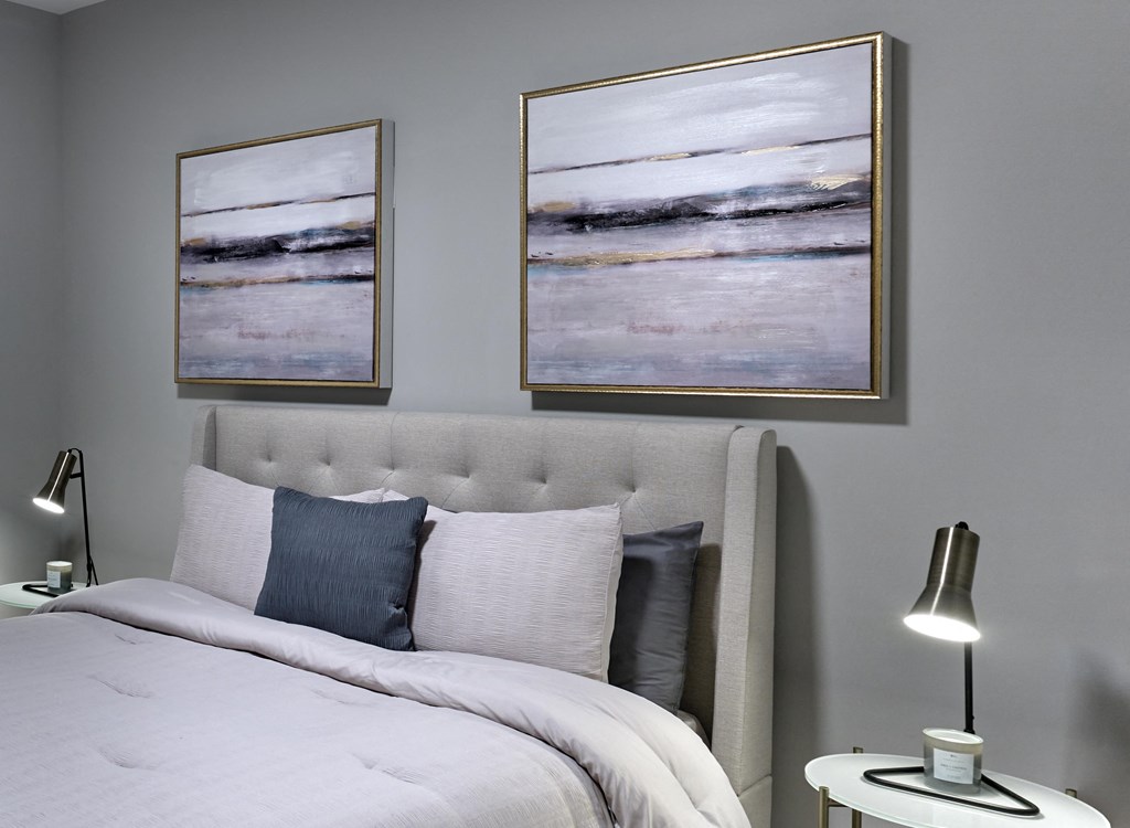 A bedroom with a large bed and two framed pictures on the wall.