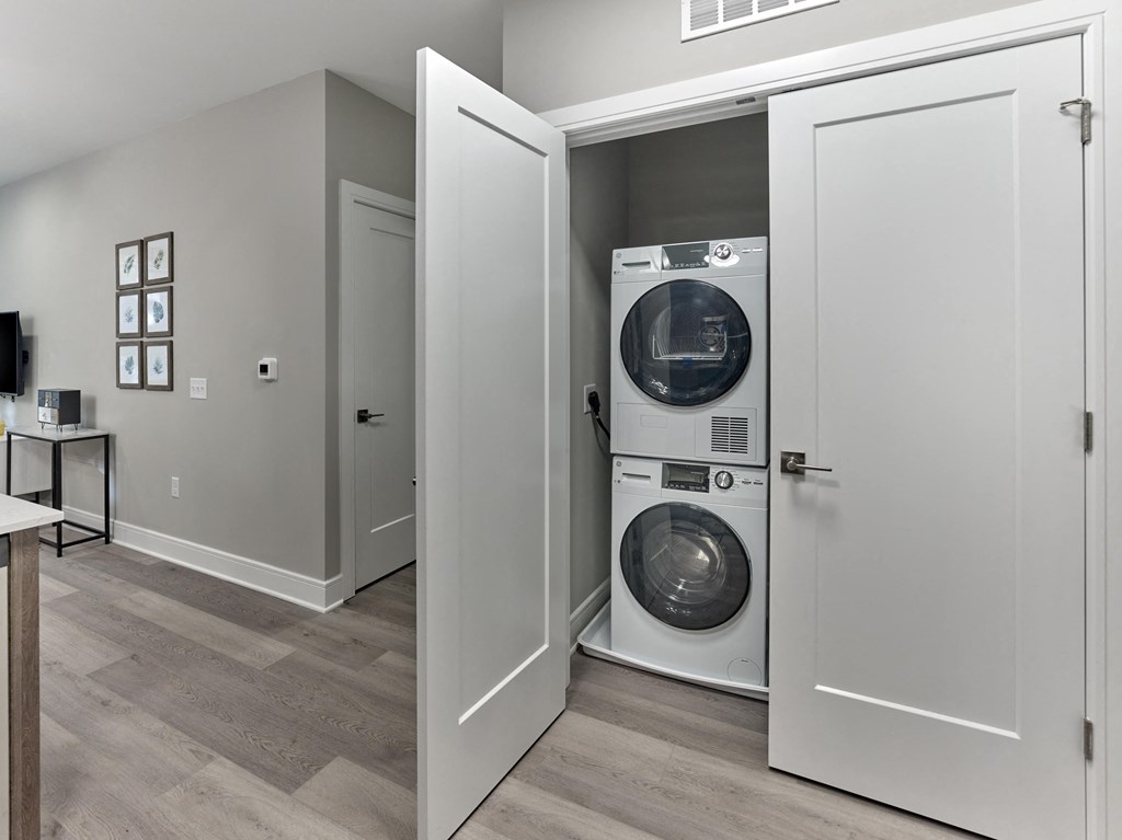 A white door is open to reveal a washer and dryer.