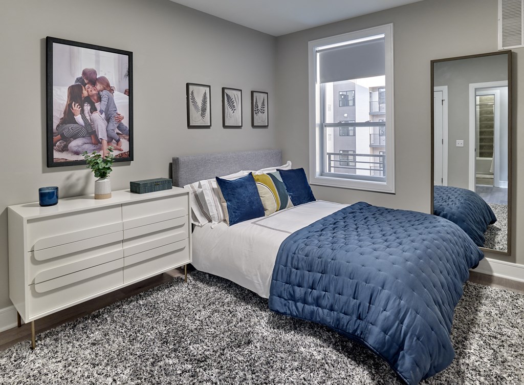 a bedroom with a bed and a dresser with a mirror