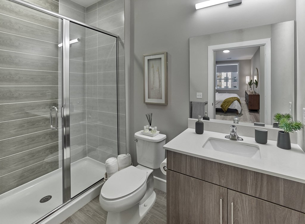 A modern bathroom with a walk-in shower, toilet, and double sink vanity.