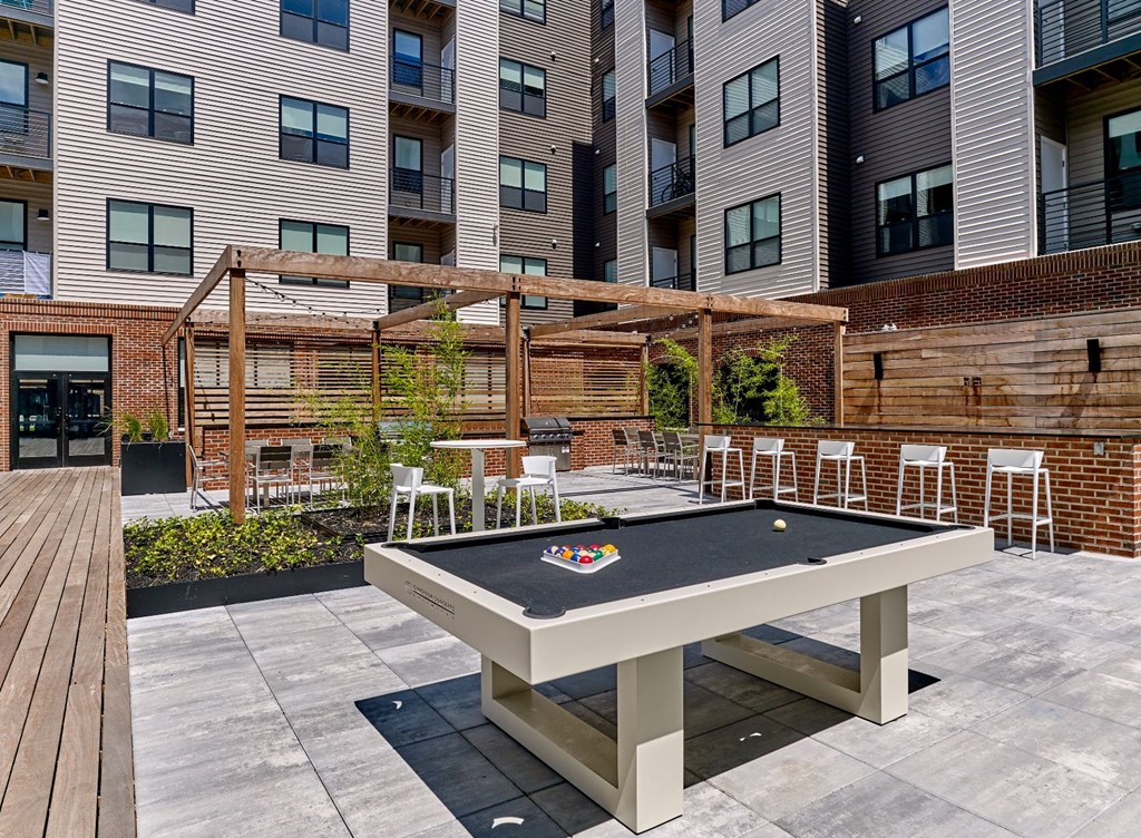 A pool table is surrounded by chairs in a courtyard.