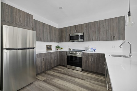 A modern kitchen with a stainless steel refrigerator and wooden cabinets.