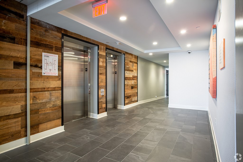 A hallway with a red exit sign above the door.