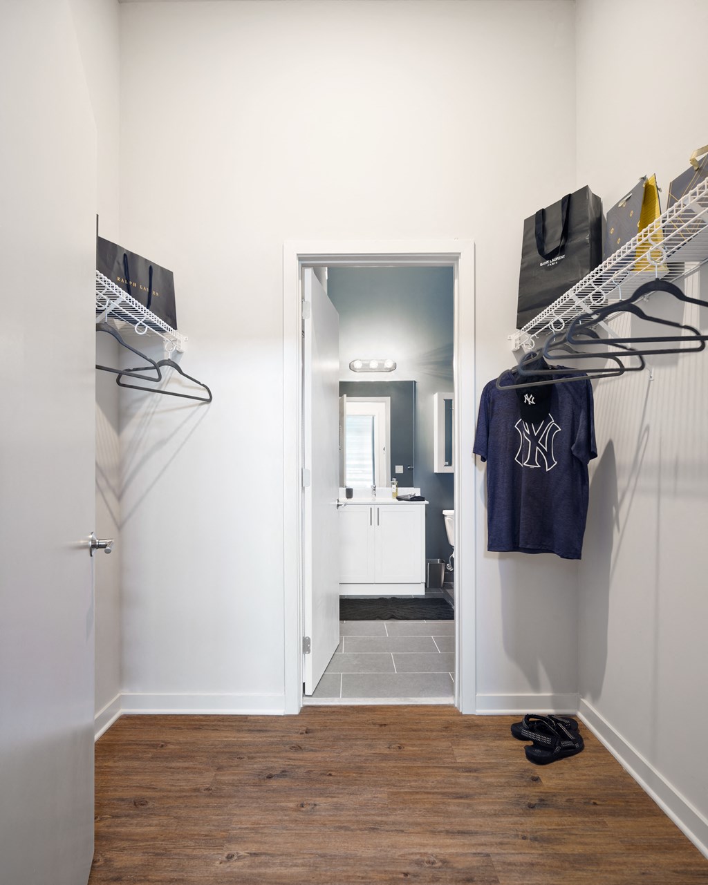 a walk in closet in a home with white walls and a door to a bathroom