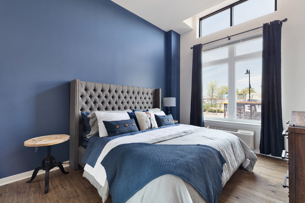 a bedroom with a bed and blue walls and a large window