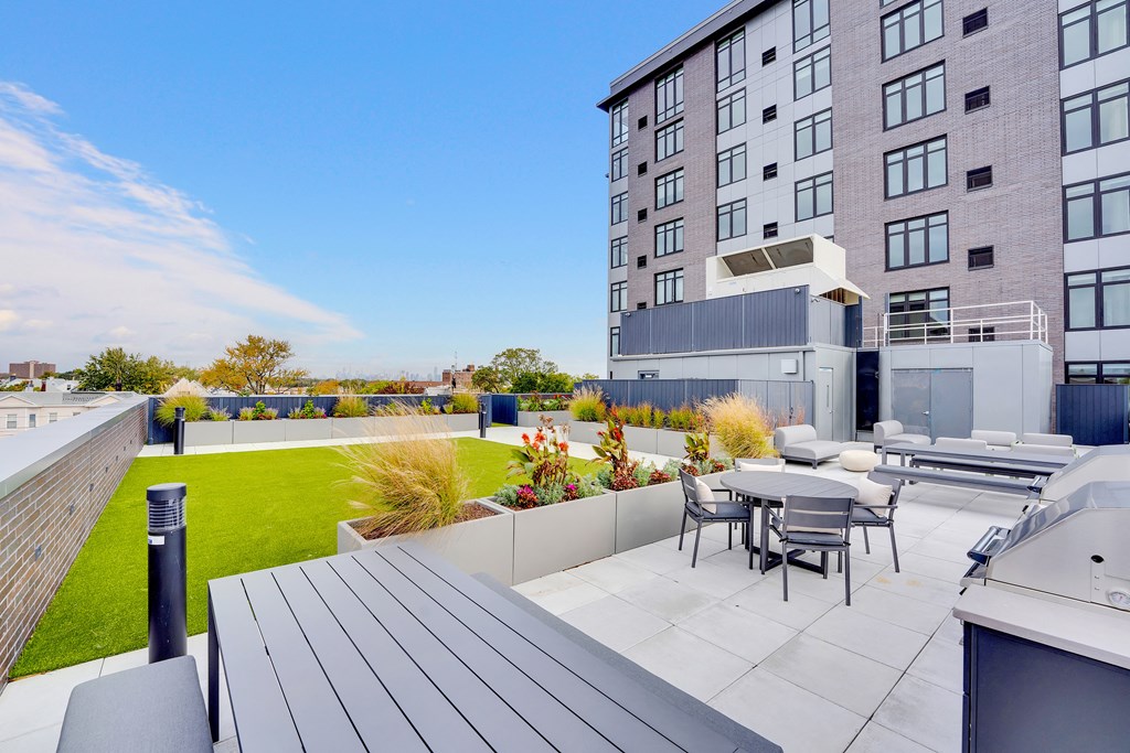 a patio with a table and chairs on a roof terrace with an apartment building
