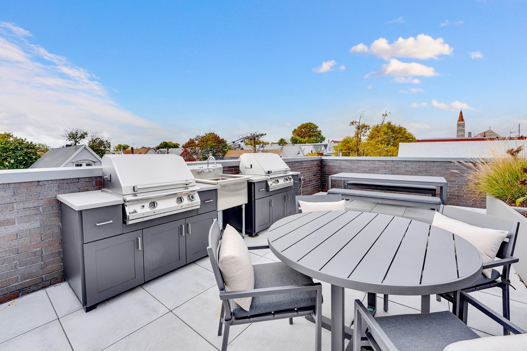 an outdoor patio with stainless steel appliances and a table and chairs