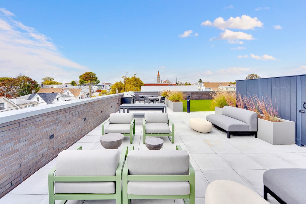 a rooftop terrace with couches and tables and a brick wall
