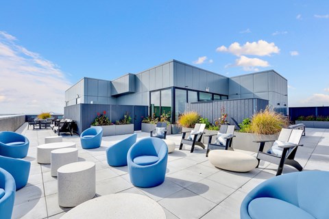 a roof terrace with blue chairs and tables with a building in the background