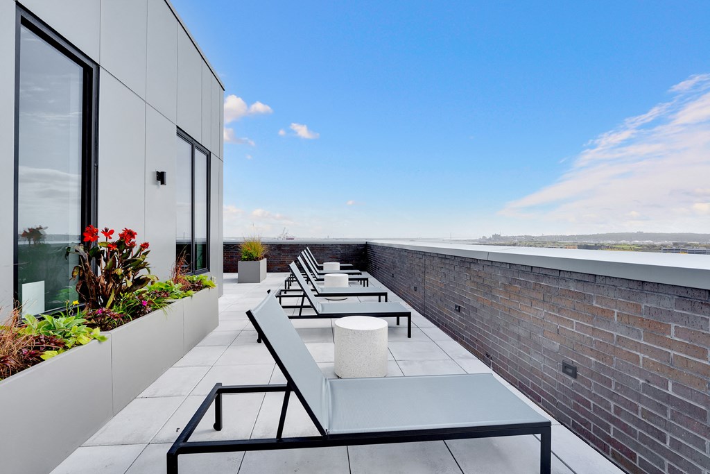 a rooftop terrace with tables and chairs and a brick wall