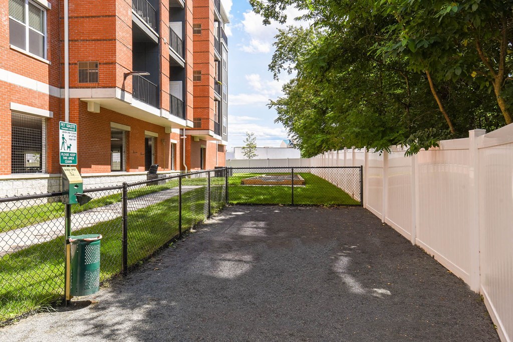 a fenced in area with a tennis court in front of a building