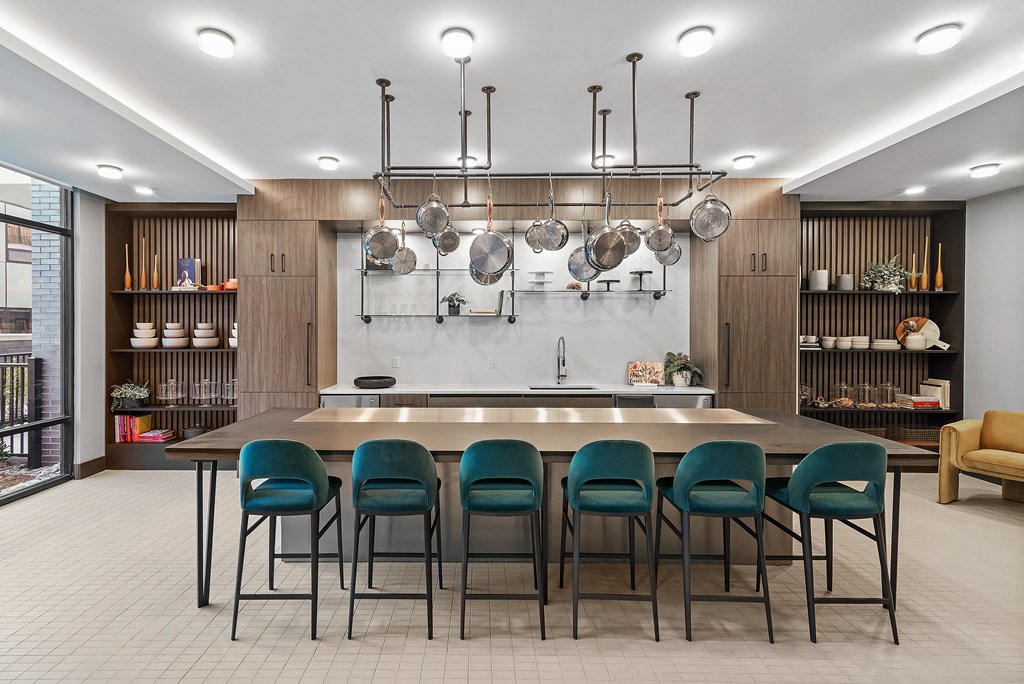 a kitchen with a long island with blue chairs and pots and pans hanging above it