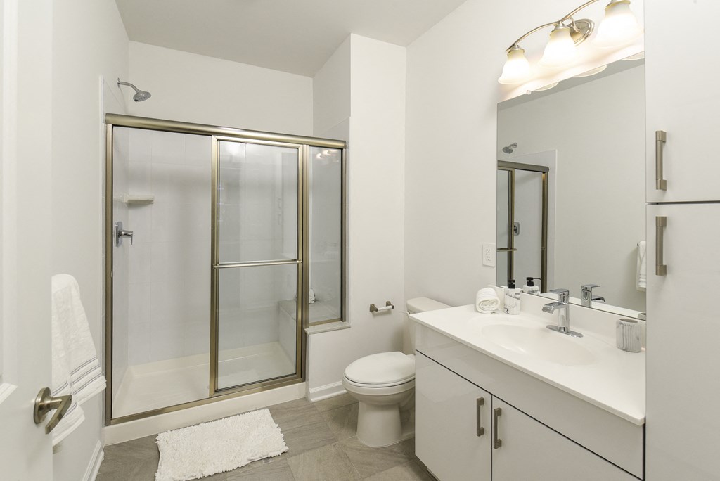 a white bathroom with a shower toilet and sink
