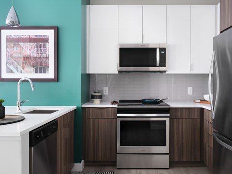 A modern kitchen with a stainless steel refrigerator, a microwave above the stove, and a sink with a faucet.