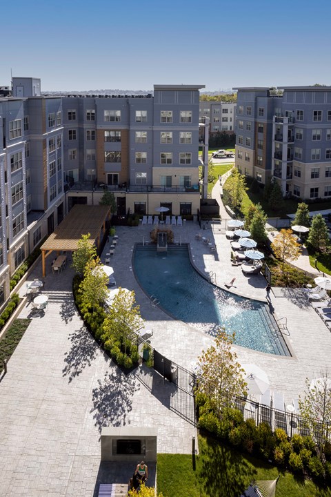 A large swimming pool is surrounded by a patio and a building.