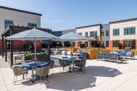 an outdoor patio with tables and umbrellas on a sunny day