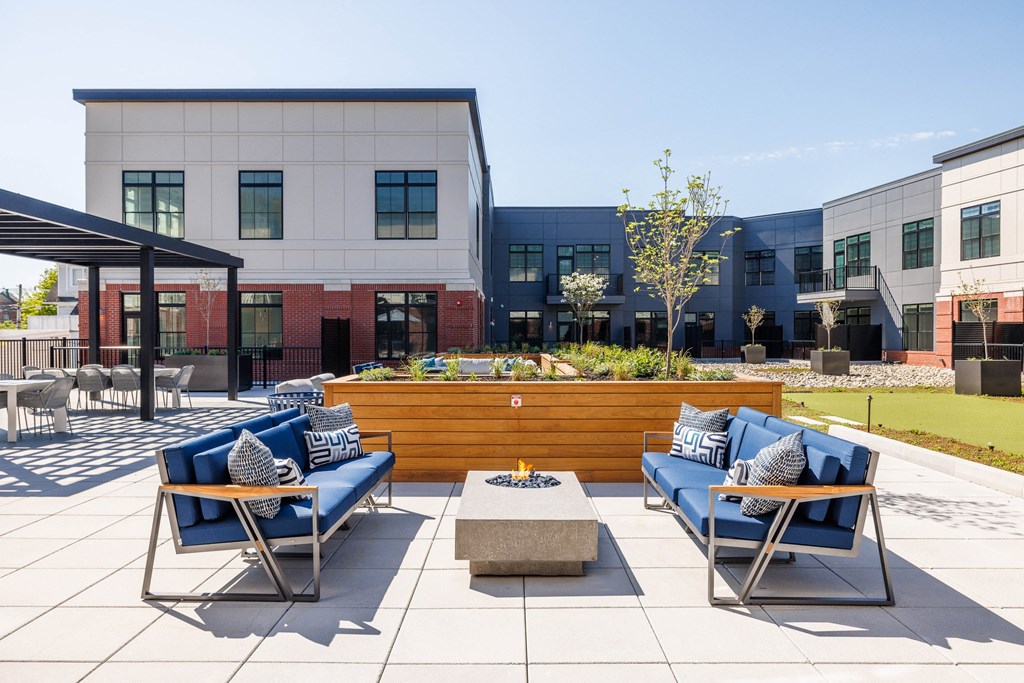 an outdoor patio with blue couches and chairs and a fire pit