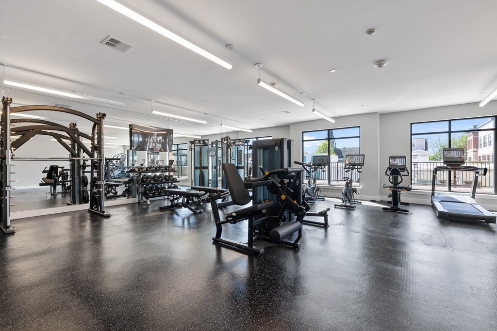 a gym with weights and other exercise equipment in a building with windows