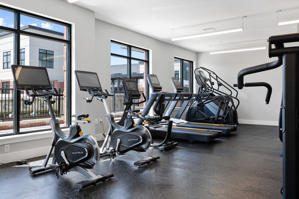 a gym with treadmills and other exercise equipment and windows