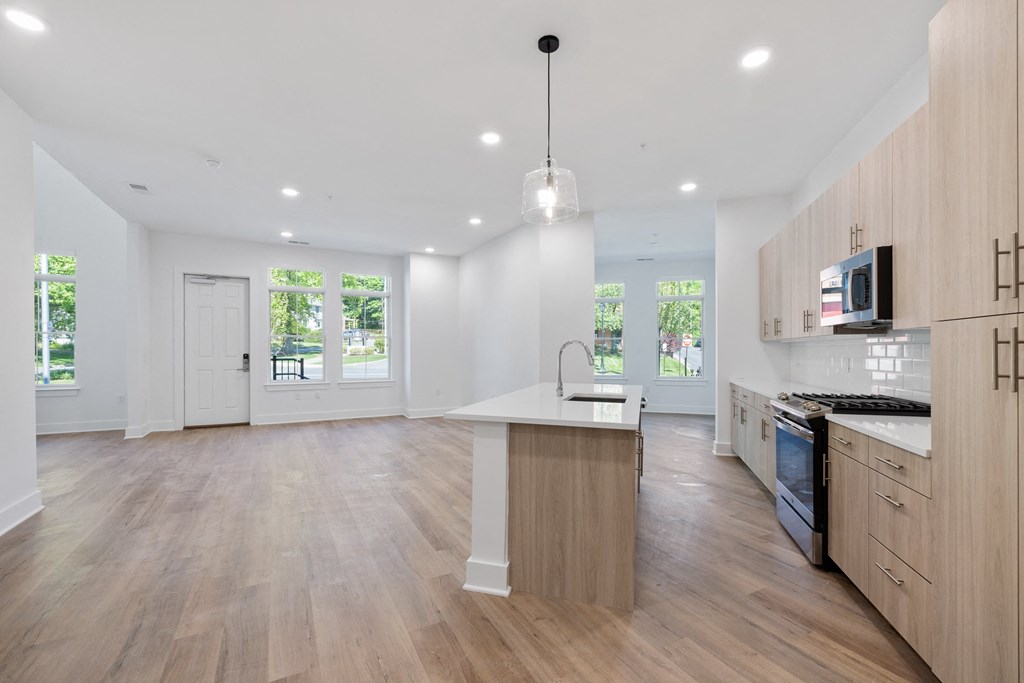 a large white room with a spiral staircase and a kitchen with wood floors