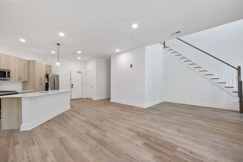 a kitchen and living room with white walls and wood floors
