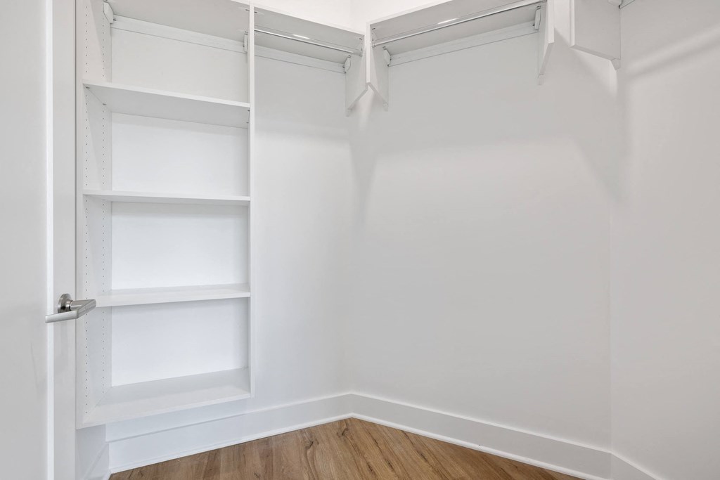 a closet with white walls and shelves and a wood floor