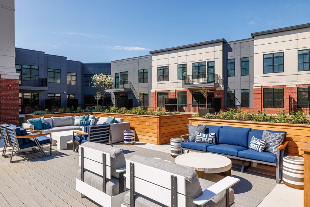 an outdoor patio area with couches tables and chairs and a building in the background
